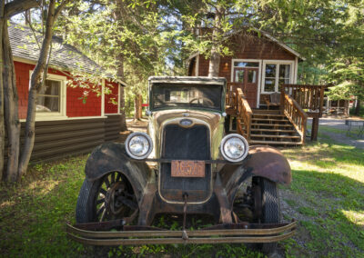 Cabin and antique car in forest at Johnston Canyon Lodge and Bungalows in Banff National Park